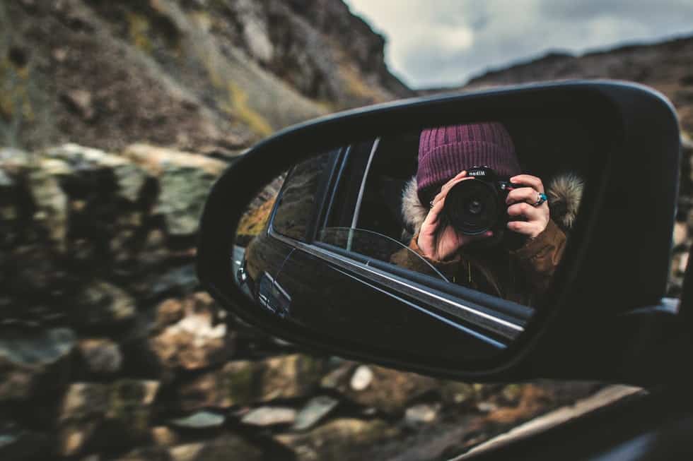 woman with camera in rearview mirror